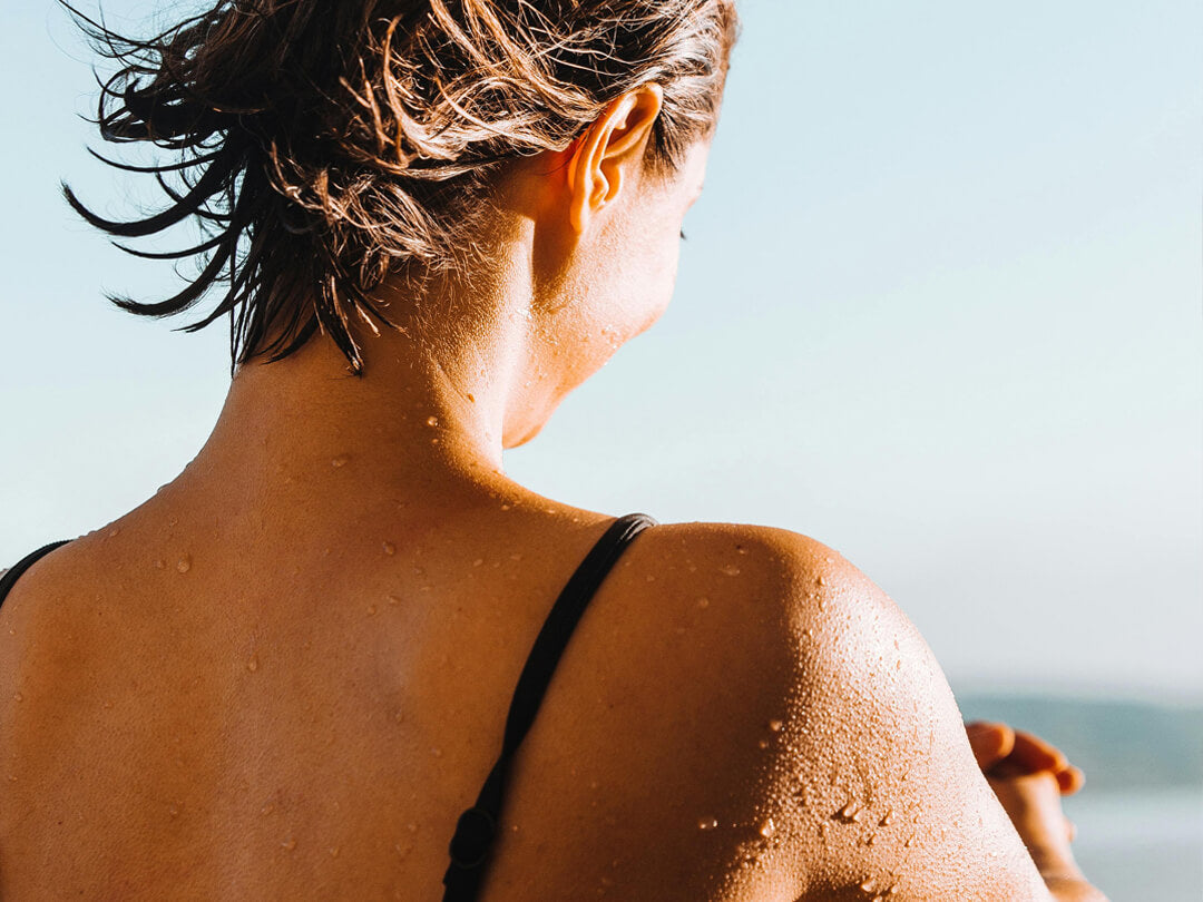 Frau im Badeanzug sitzt am Strand